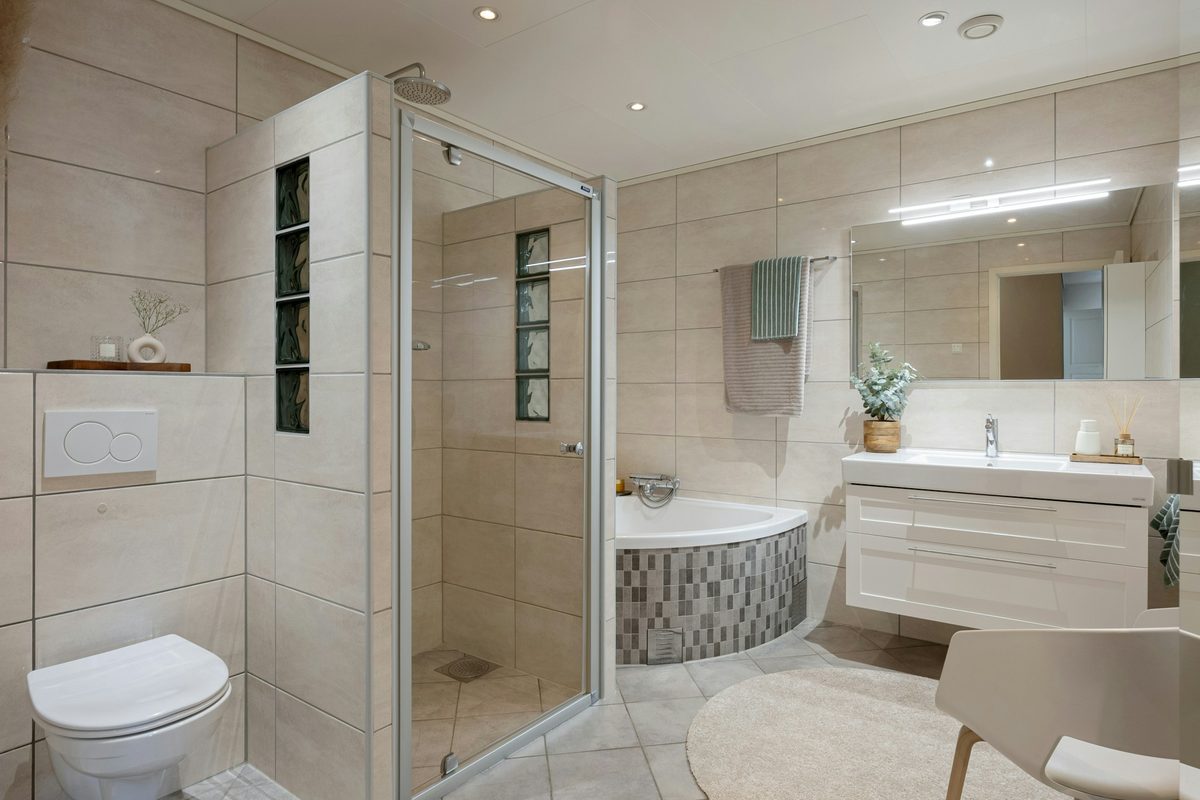 Afgewerkte badkamer met wand- en vloertegels, hangtoilet, douche, bad en badkamermeubel