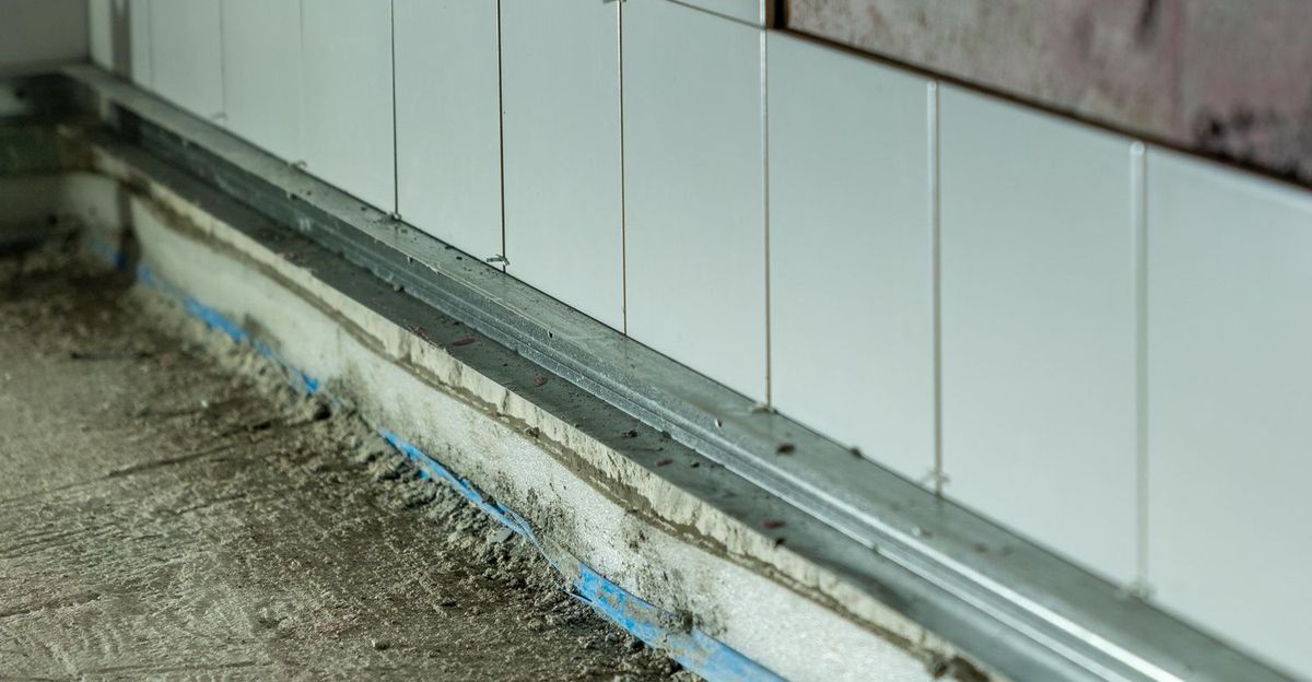 Witte wandtegels op een metalen lat boven de vloer